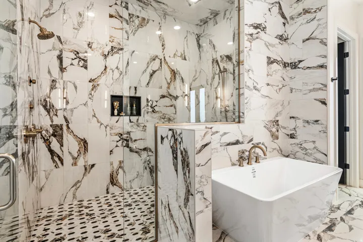 Spa-inspired bath featuring a frameless glass shower enclosure with brass fixtures, a built-in shower niche, and a freestanding soaking tub