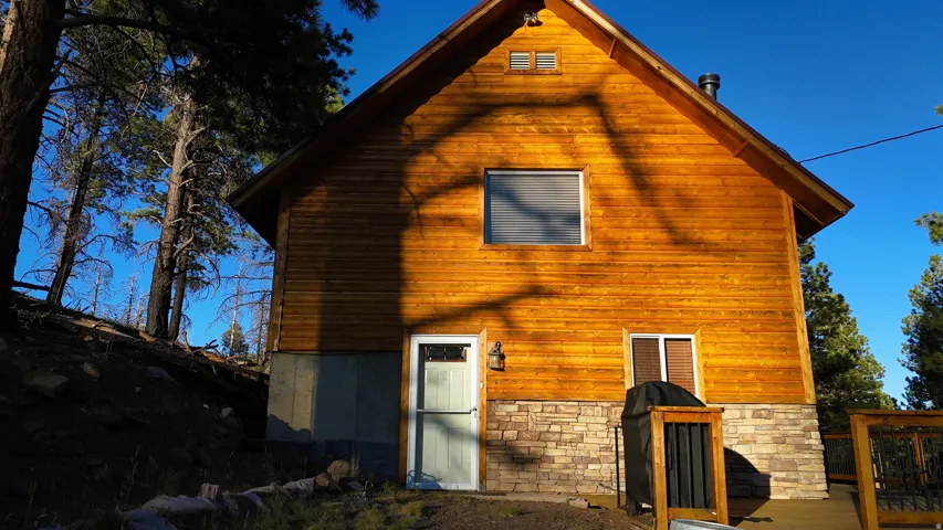 Wood-sided exterior featuring a stone-clad foundation and a peaked roofline