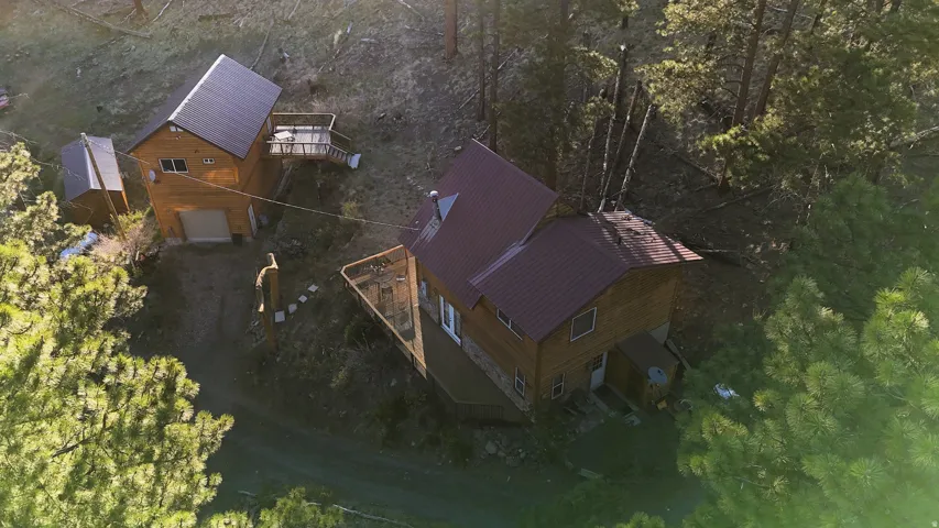 Two rustic-style dwellings featuring wood siding, stone accents, and red metal roofs