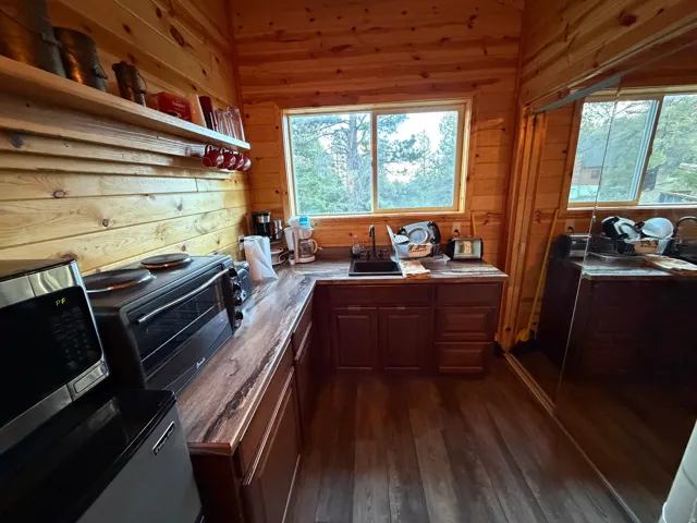 Kitchen area featuring wood-finish flooring, wood plank walls, and a corner sink with a window