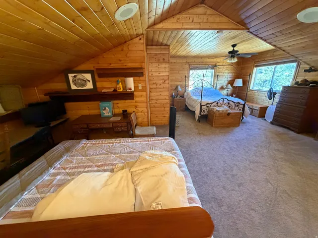 Wood-paneled room featuring vaulted ceilings, recessed lighting, and wall-mounted shelving