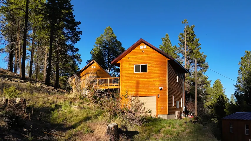 Wood-sided residential structure featuring a gable roof, integrated garage, and multiple windows