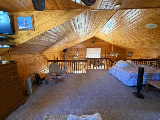 Spacious loft area featuring wood-paneled walls and ceiling, pitched ceiling design, recessed lighting, and a built-in railing system