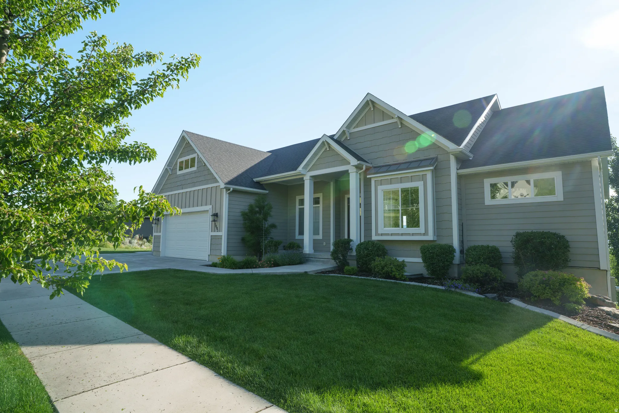 Contemporary single-story residence with a multi-gable roofline and light green siding