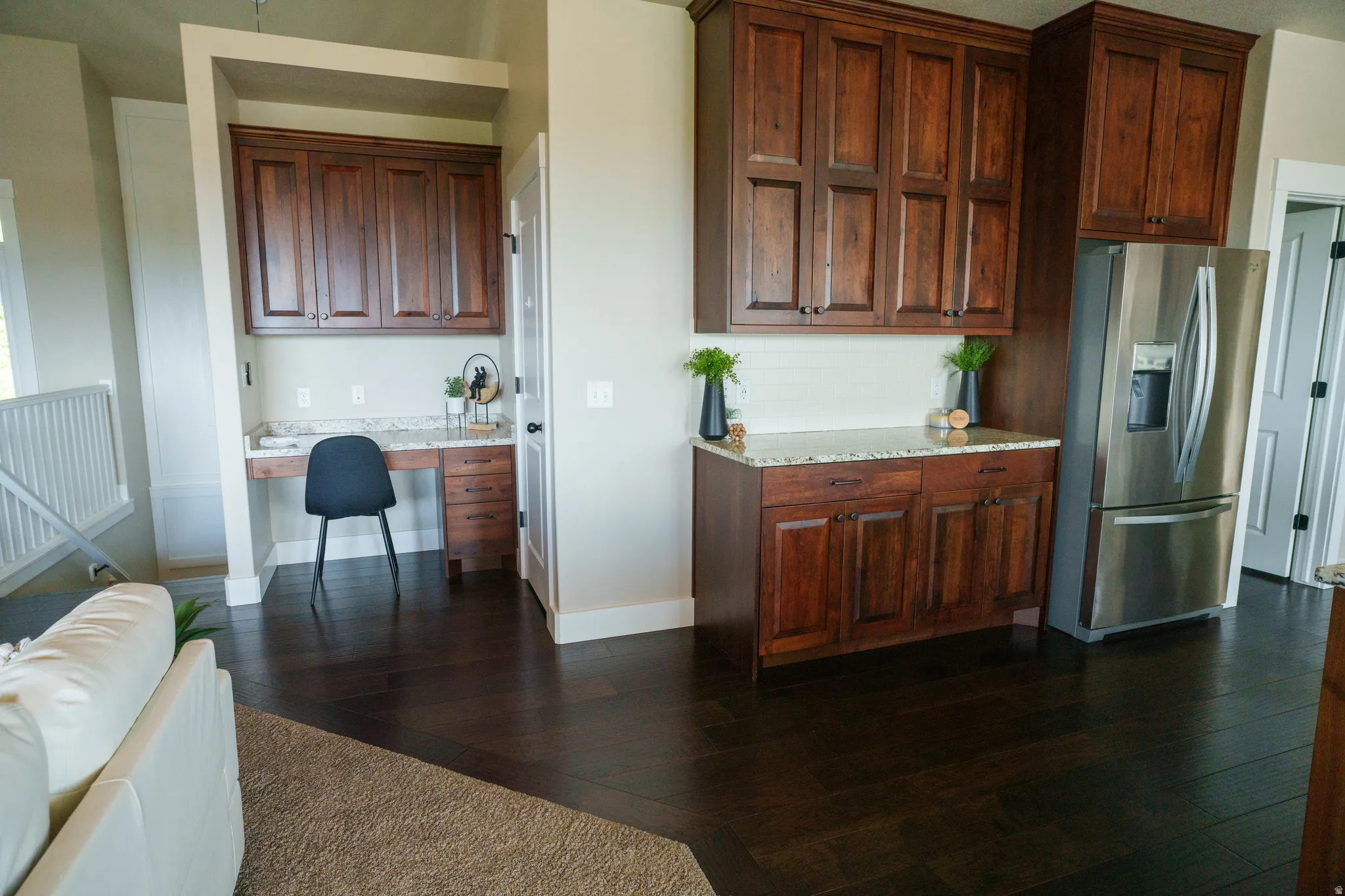 Built-in desk area with upper cabinetry and granite-style countertop, complemented by dark wood-finish flooring