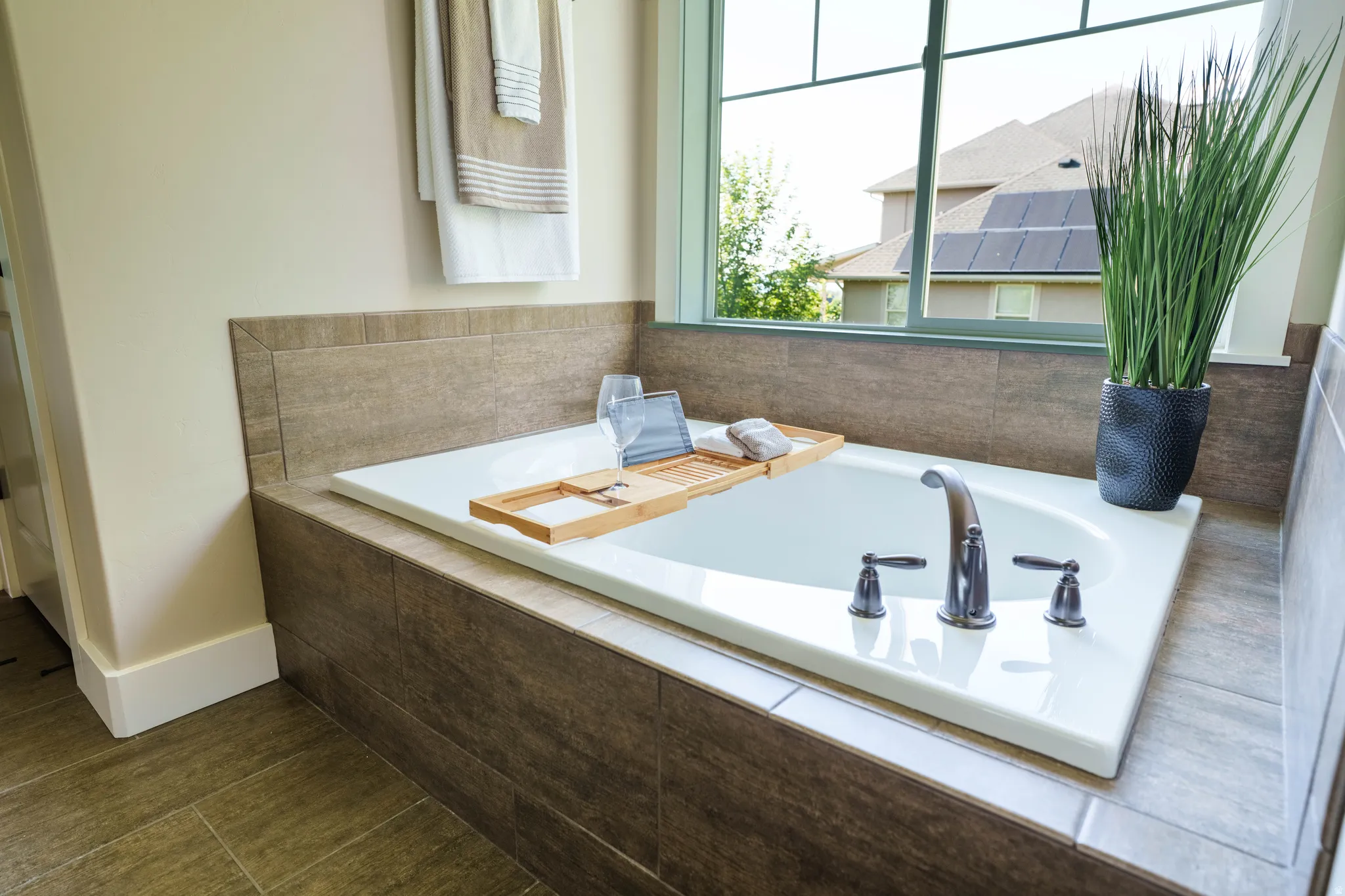 Built-in soaking tub with deck-mounted fixtures, surrounded by neutral-toned tile