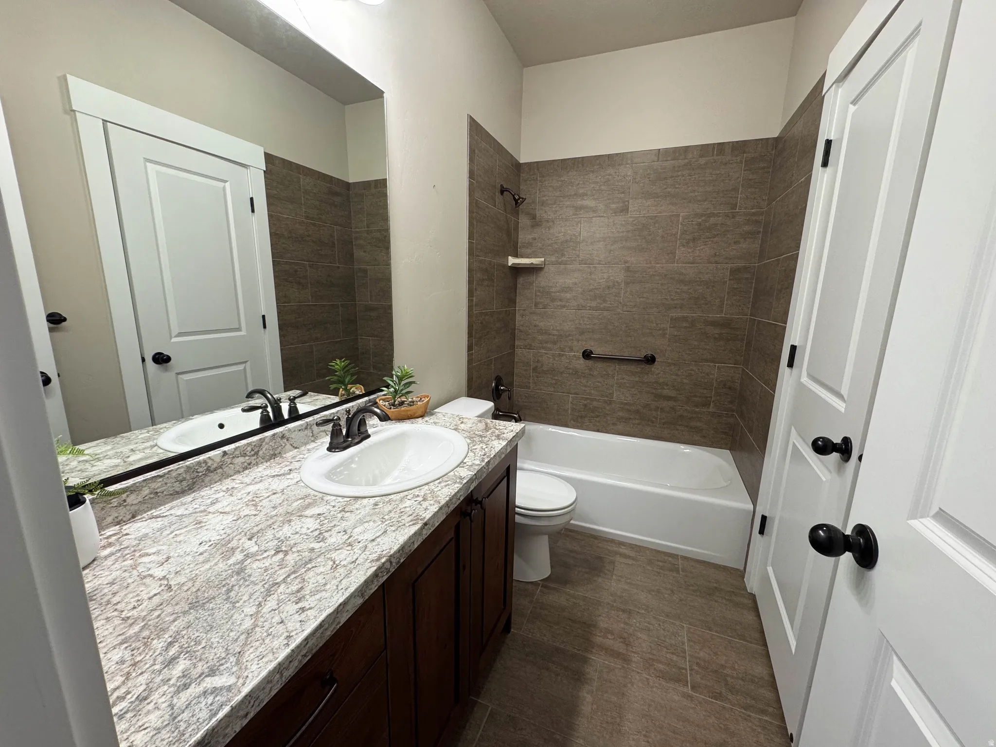 Bathroom featuring a single vanity with an undermount sink, a patterned countertop, and dark wood cabinetry