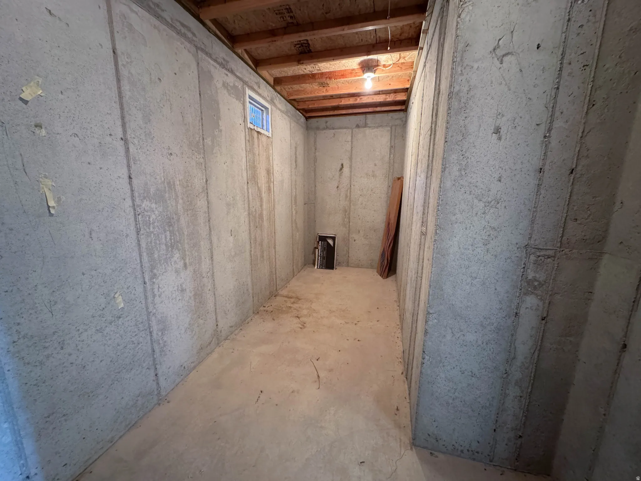 Unfinished basement room featuring poured concrete walls and concrete flooring