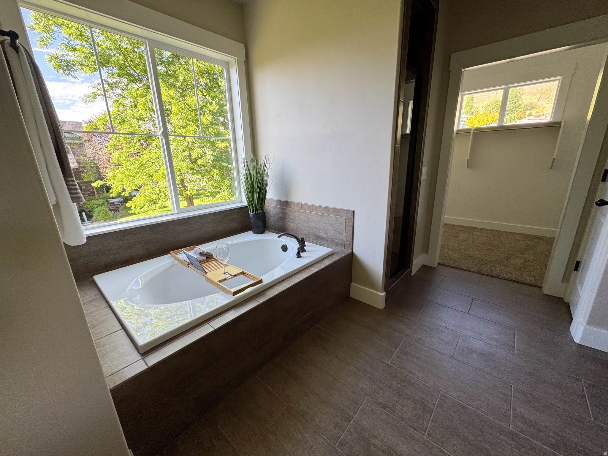 Built-in soaking tub with dark bronze fixtures and a large window