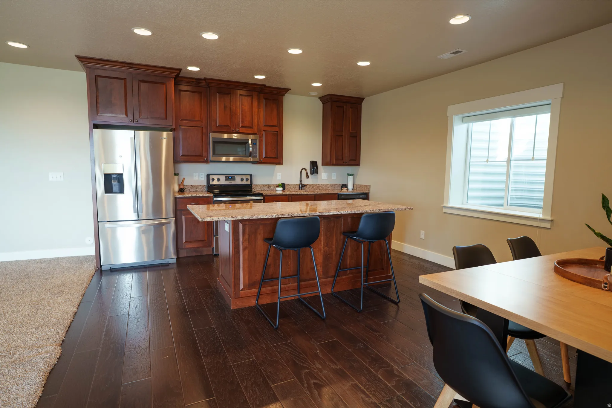 Kitchen featuring dark wood-finish cabinetry, stainless steel appliances, and a central island with a breakfast bar