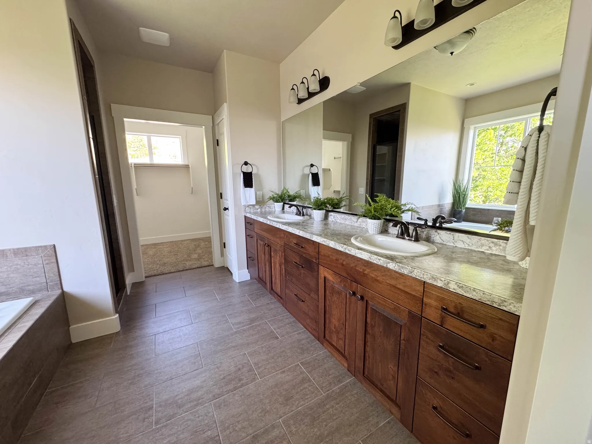 Dual vanity with undermount sinks, wood cabinetry, and a light-toned countertop