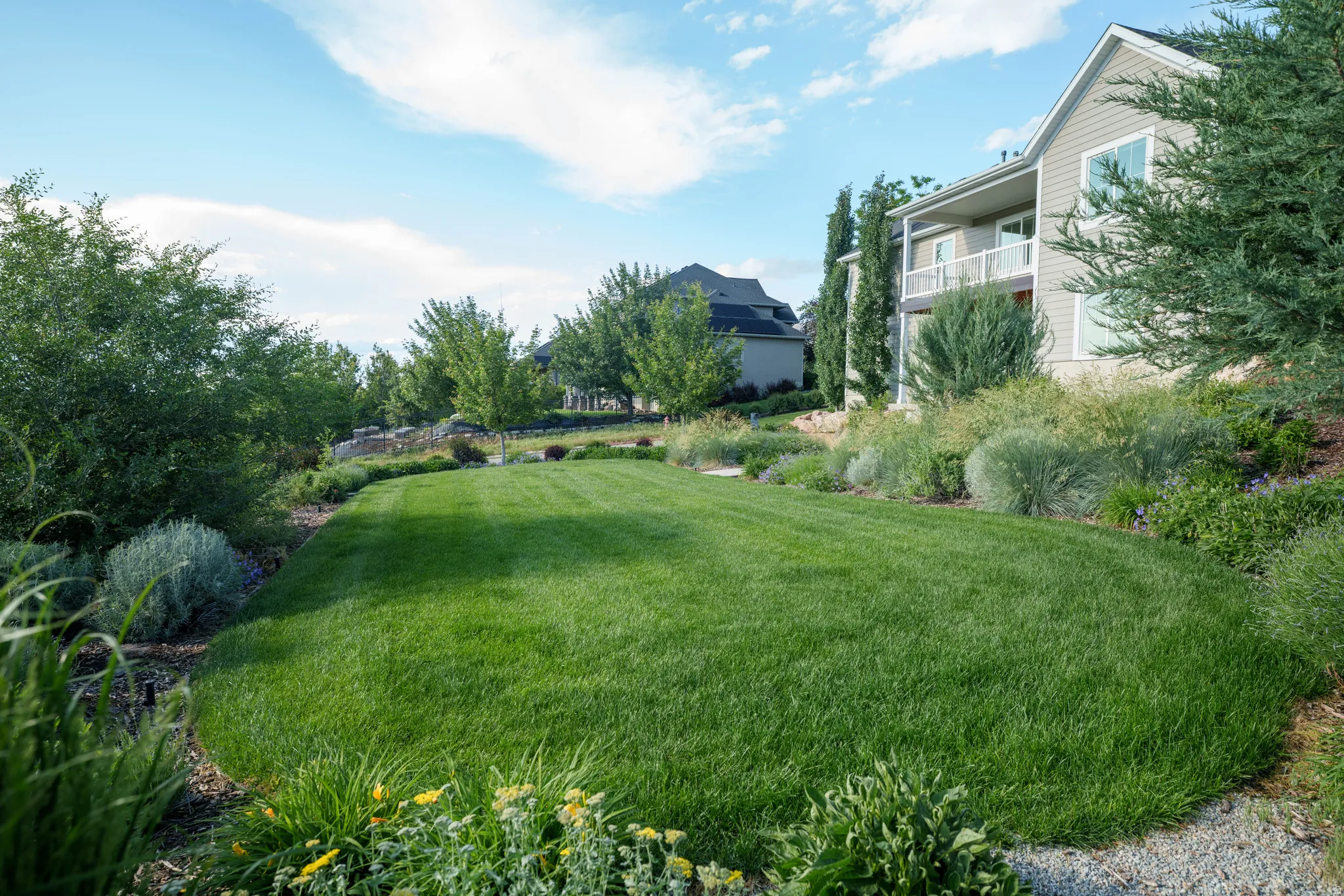 Expansive manicured lawn bordered by diverse shrubbery and mature trees