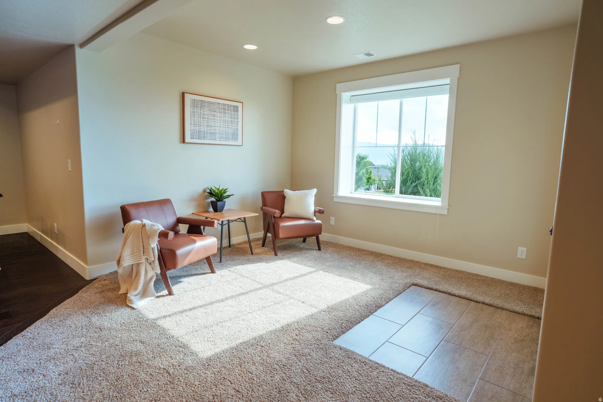 Carpeted interior space with a large window, recessed lighting, and a partial wood-finish flooring area