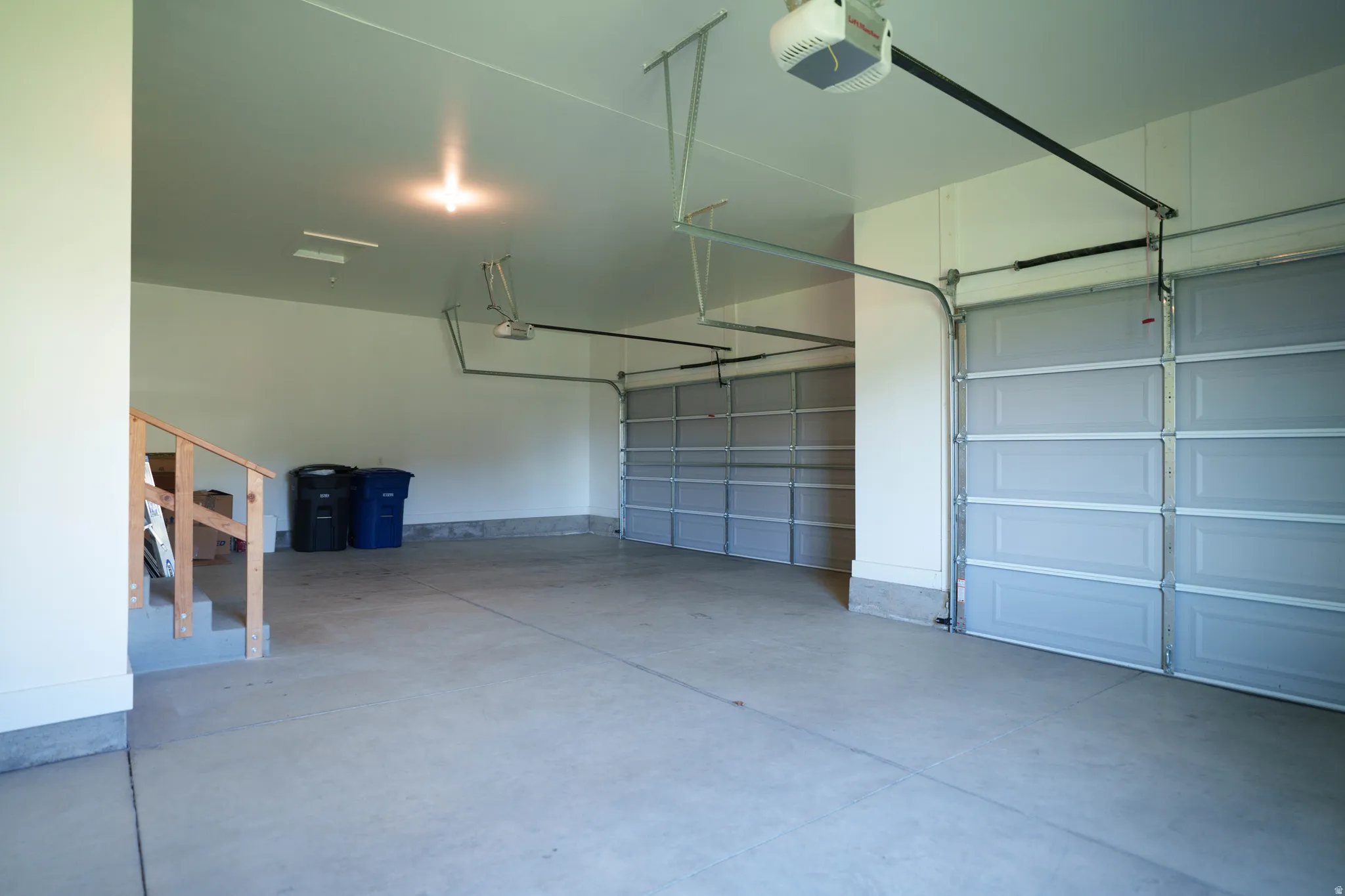 Spacious two-car garage featuring a concrete floor, light-colored walls, and automatic garage door openers
