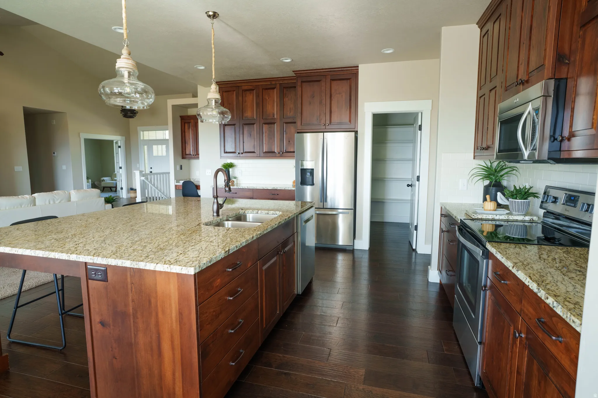 Spacious kitchen featuring an expansive island with an undermount sink, granite countertops, and rich wood cabinetry