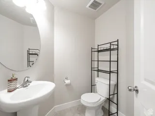 Contemporary powder room featuring a pedestal sink with a chrome faucet, an oval mirror, and light gray walls