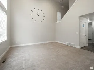 Spacious room with high ceilings, light neutral wall paint, and light-colored carpeting