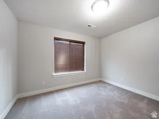 Interior room with neutral gray wall paint, gray carpet, and white baseboards