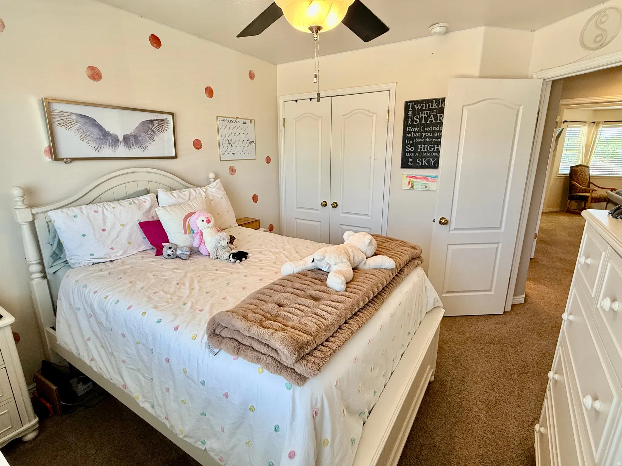 Carpeted room featuring a white arched headboard, built-in dual-door closet, and a ceiling fan with integrated lighting