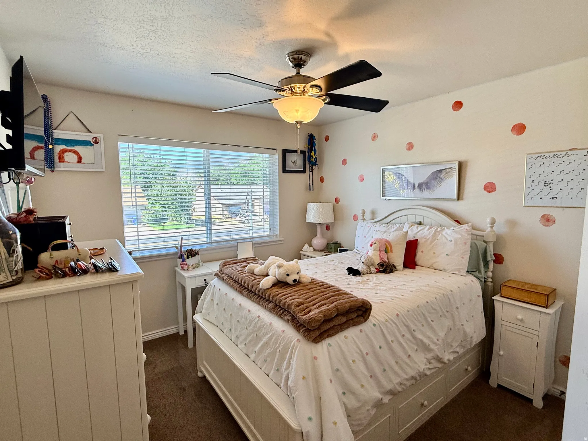 Carpeted room featuring a ceiling fan with integrated lighting, a broad window with horizontal blinds, and a built-in bed frame with storage drawers