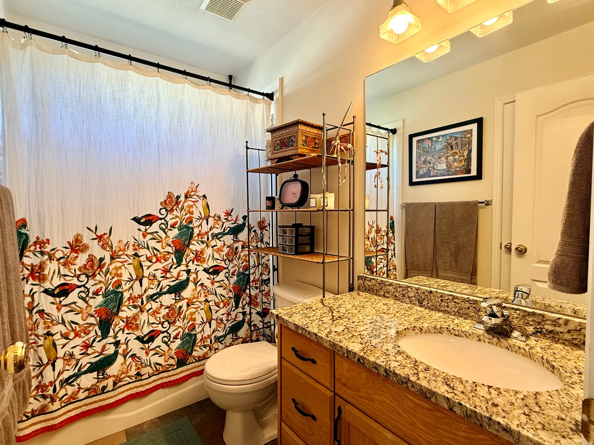 Bathroom featuring a granite-finish countertop, wood-finish vanity cabinetry, and an integrated sink with a chrome-finish faucet