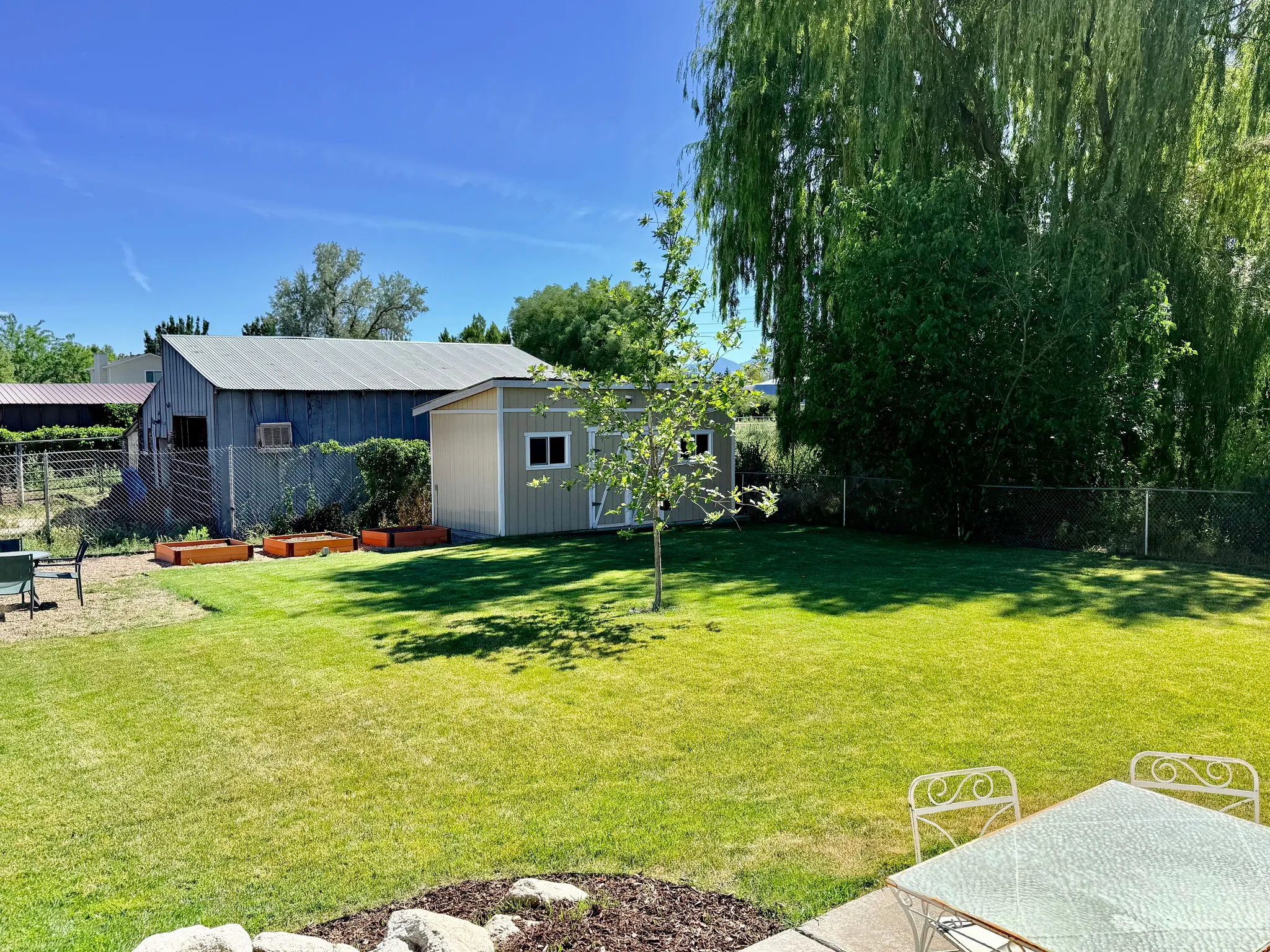 Spacious backyard featuring a manicured lawn, a detached storage shed, and a large barn structure