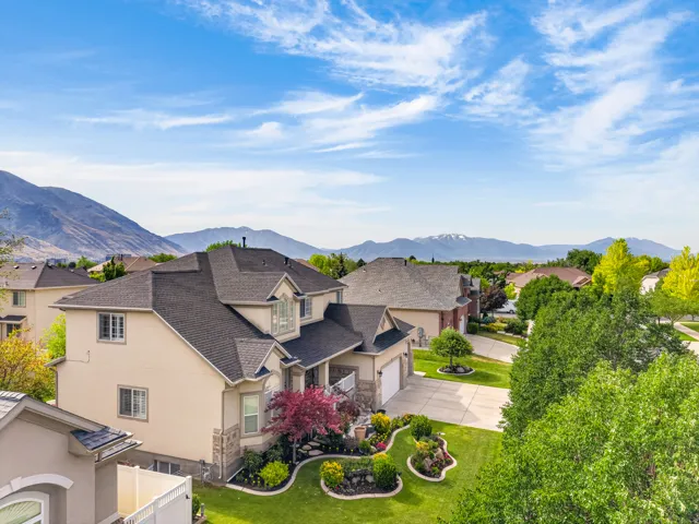 Traditional-style residence featuring a dark shingle roof, light-colored stucco siding, and stone accents