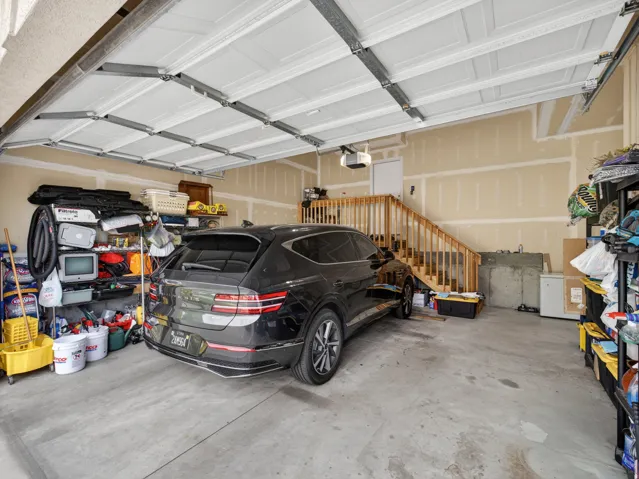Spacious garage with a concrete floor, finished walls, and a built-in staircase with wood railings