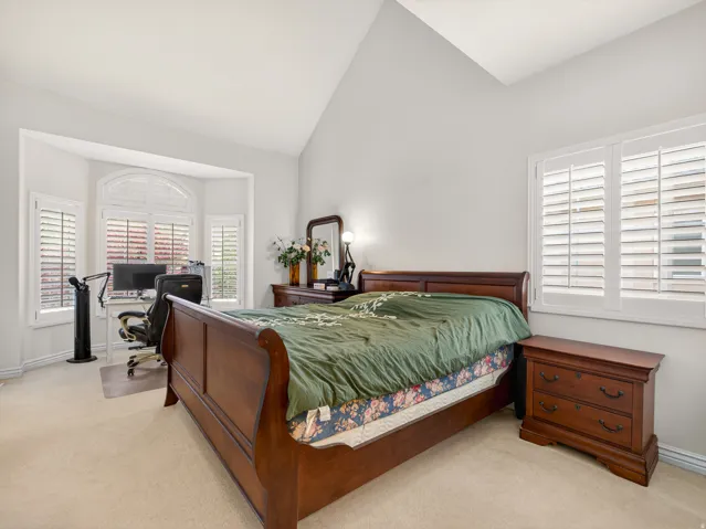 Bright room featuring a vaulted ceiling and light-toned carpet