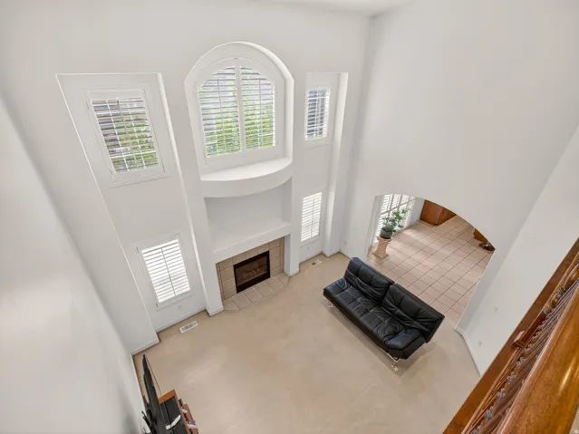 Two-story living area featuring a fireplace with a tile surround, arched windows with shutters, and additional windows with shutters