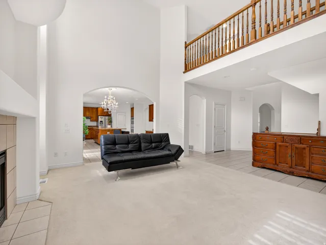 Two-story living area featuring a prominent fireplace with tile surround, vaulted ceilings, and an upper-level wood railing