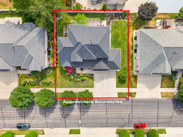 Aerial view showcasing a property with a multi-gabled roof, extensive green lawn, and mature landscaping