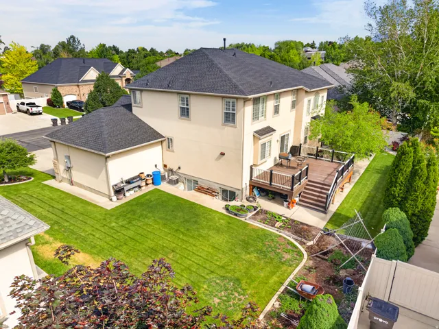 Rear elevation featuring a multi-level composite deck with dark railings, a ground-level patio, and an expansive lawn