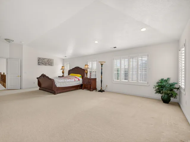 Spacious room featuring neutral carpet flooring, recessed lighting, and white plantation shutters on multiple windows