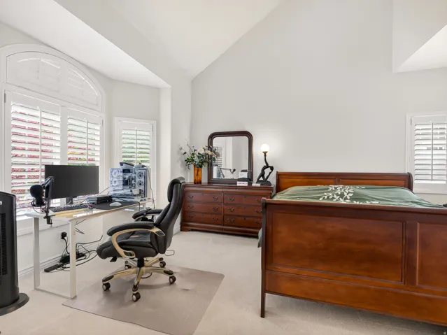 Vaulted ceilings featuring white walls and light-toned carpeting