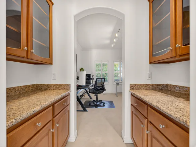 Hallway featuring built-in cabinetry with glass-front upper cabinets and wood base cabinets