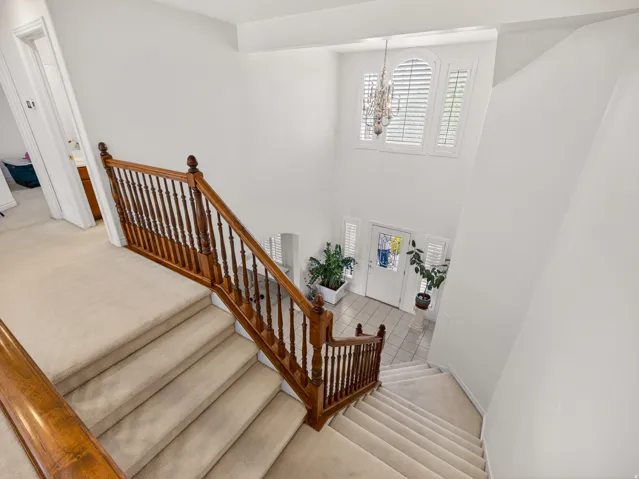 Grand entryway featuring a two-story ceiling, a decorative chandelier, and an arched window with plantation shutters
