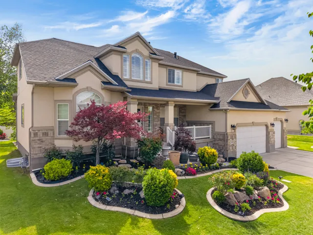 Stucco and stone exterior featuring multiple gables, an arched window, and a covered porch with white railing