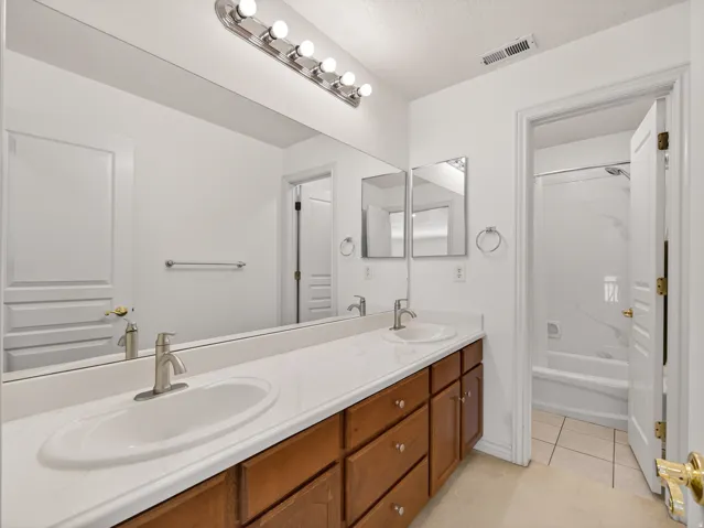 Dual vanity with wood cabinetry and white countertops, featuring two undermount sinks and brushed nickel faucets