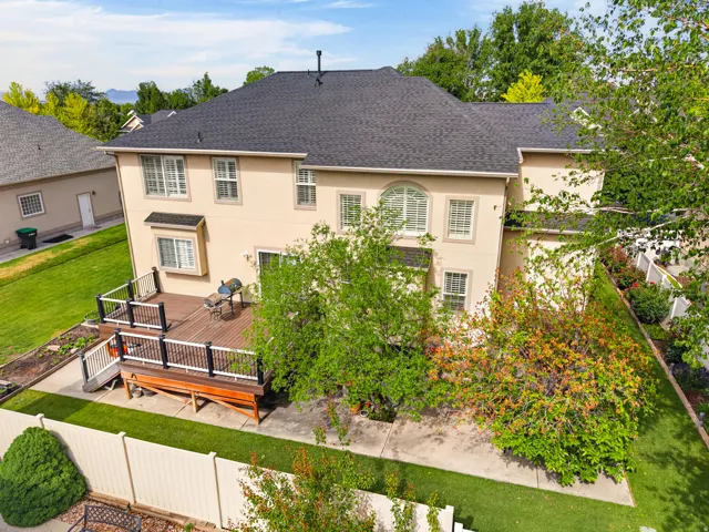 Rear elevation featuring a multi-level wood-finish deck with black and white railings, stucco siding, and a shingle roof