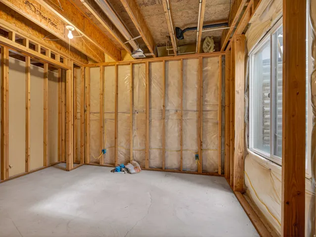 Unfinished basement space with exposed wooden framing and joists