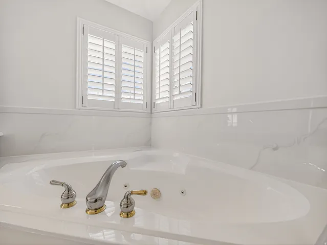 Soaking tub with jetted features, accented by polished chrome and gold-tone fixtures