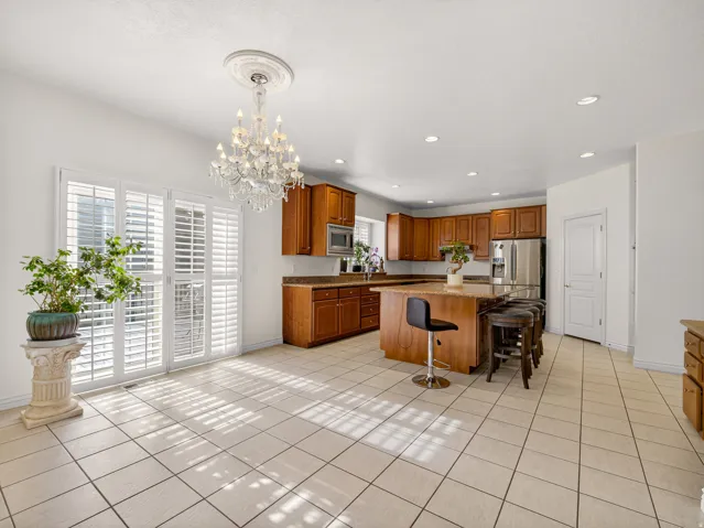 Spacious kitchen featuring a large central island with seating, ample cabinetry, stainless steel appliances, and a tiled floor