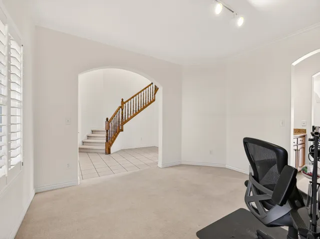 Arched doorway leading to a staircase with wood banisters and tiled flooring