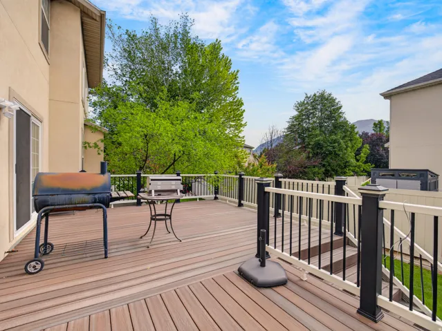 Expansive outdoor deck featuring wood-finish flooring, a white and black railing system, and exterior siding