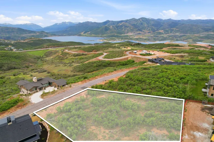 Expansive lot with defined boundaries and natural landscaping, surrounded by paved roadways and distant mountain scenery