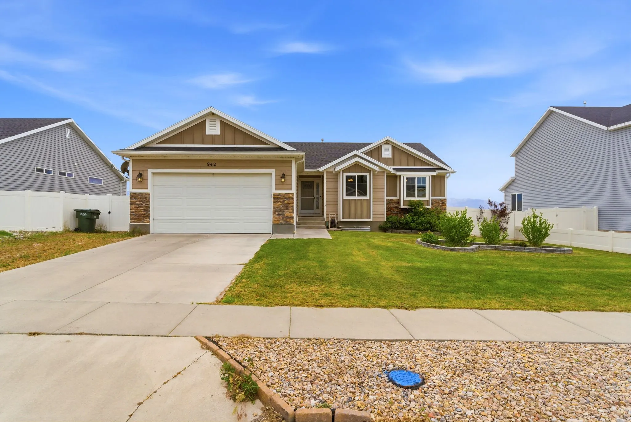 Single-story residence featuring a two-car garage, stone façade accents, bay windows, and a well-maintained front lawn with established landscaping