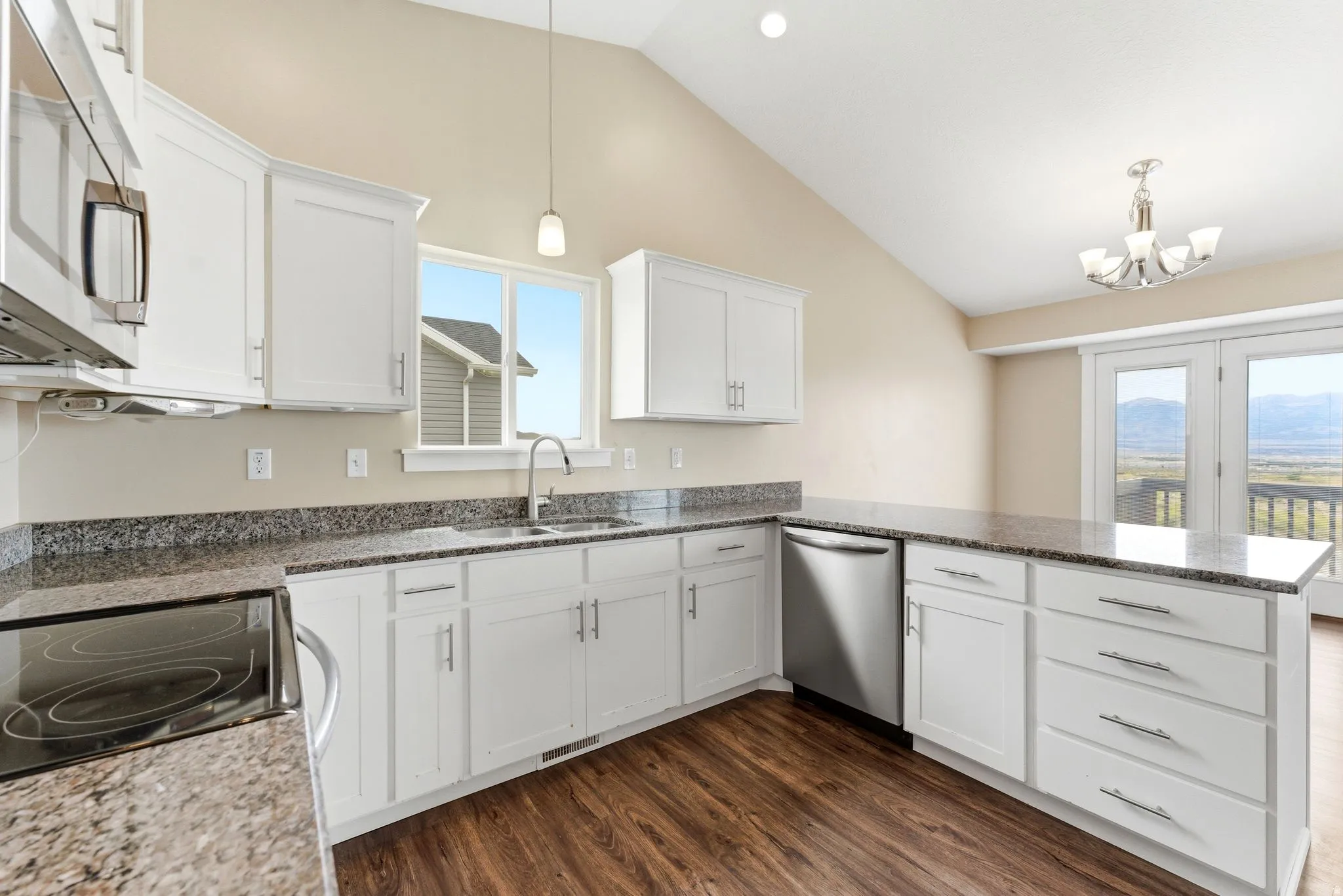 Modern kitchen featuring white cabinetry, granite-style countertops, stainless steel appliances, and wood-finish flooring