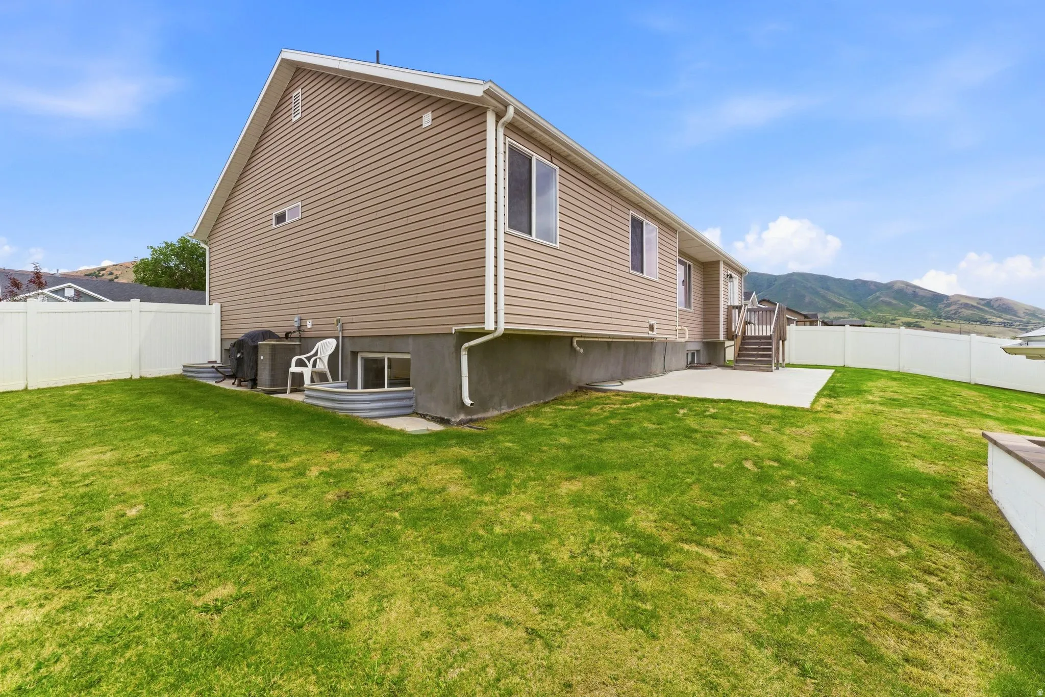 Spacious rear yard featuring an expansive lawn, concrete patio, and full privacy fencing