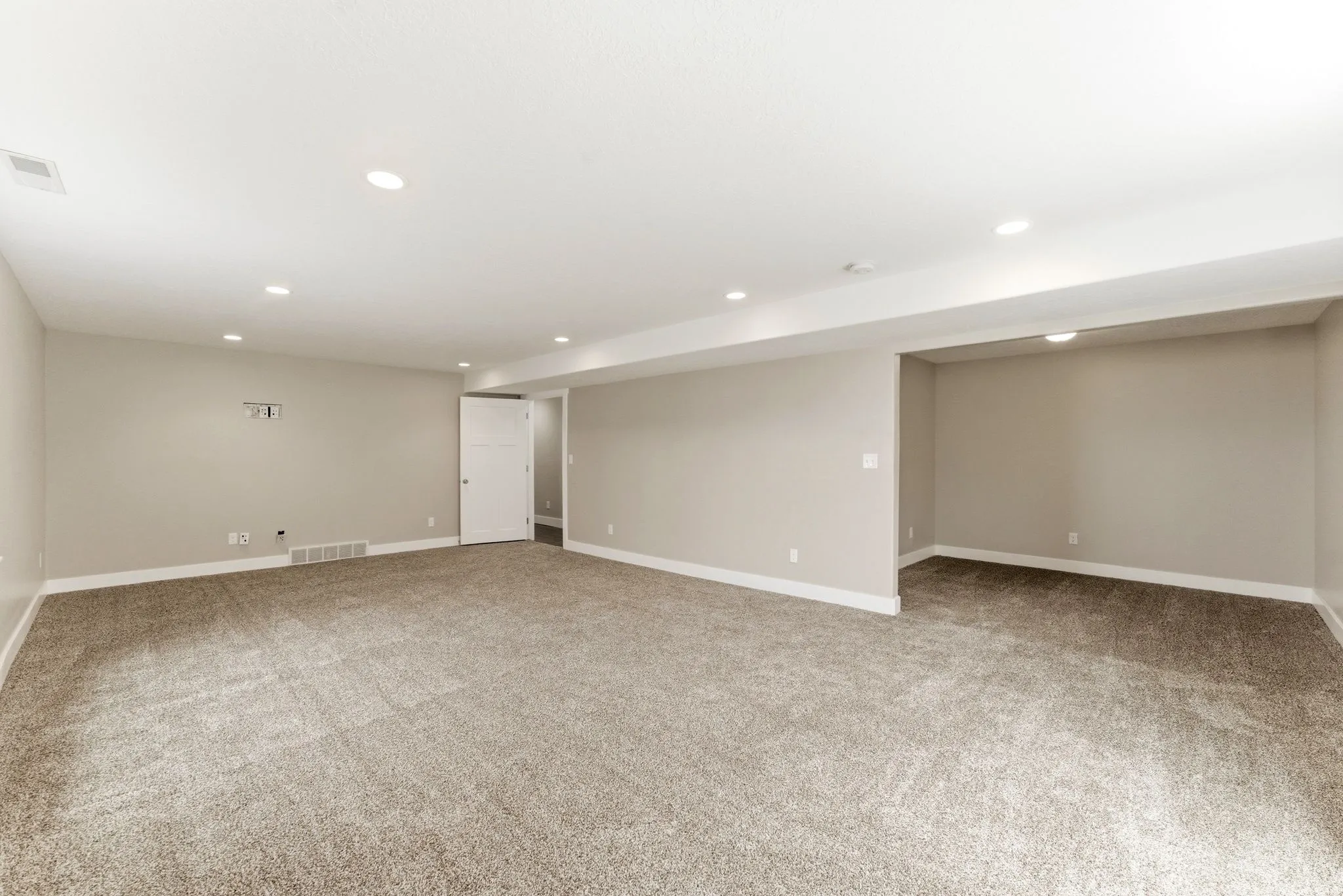 Spacious room featuring neutral carpeting, recessed lighting, and a neutral wall color